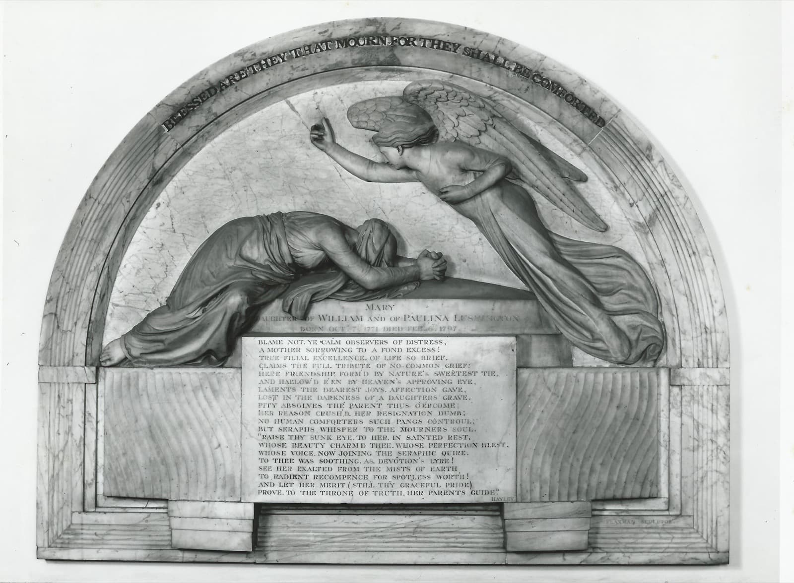 The Flaxman monument to Mary Lushington: a veiled woman lying face down across a marble sarcophagus, an angel with folded wings reaching over her, beneath an arch reading 'Blessed are they that mourn for they shall be comforted'.