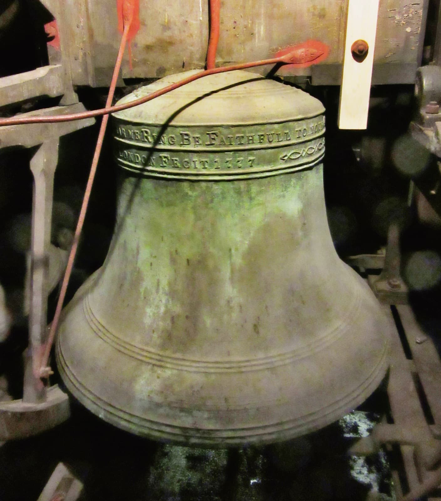 Bronze bells hanging in a wooden frame in a bell chamber, with their headstocks and wheels.