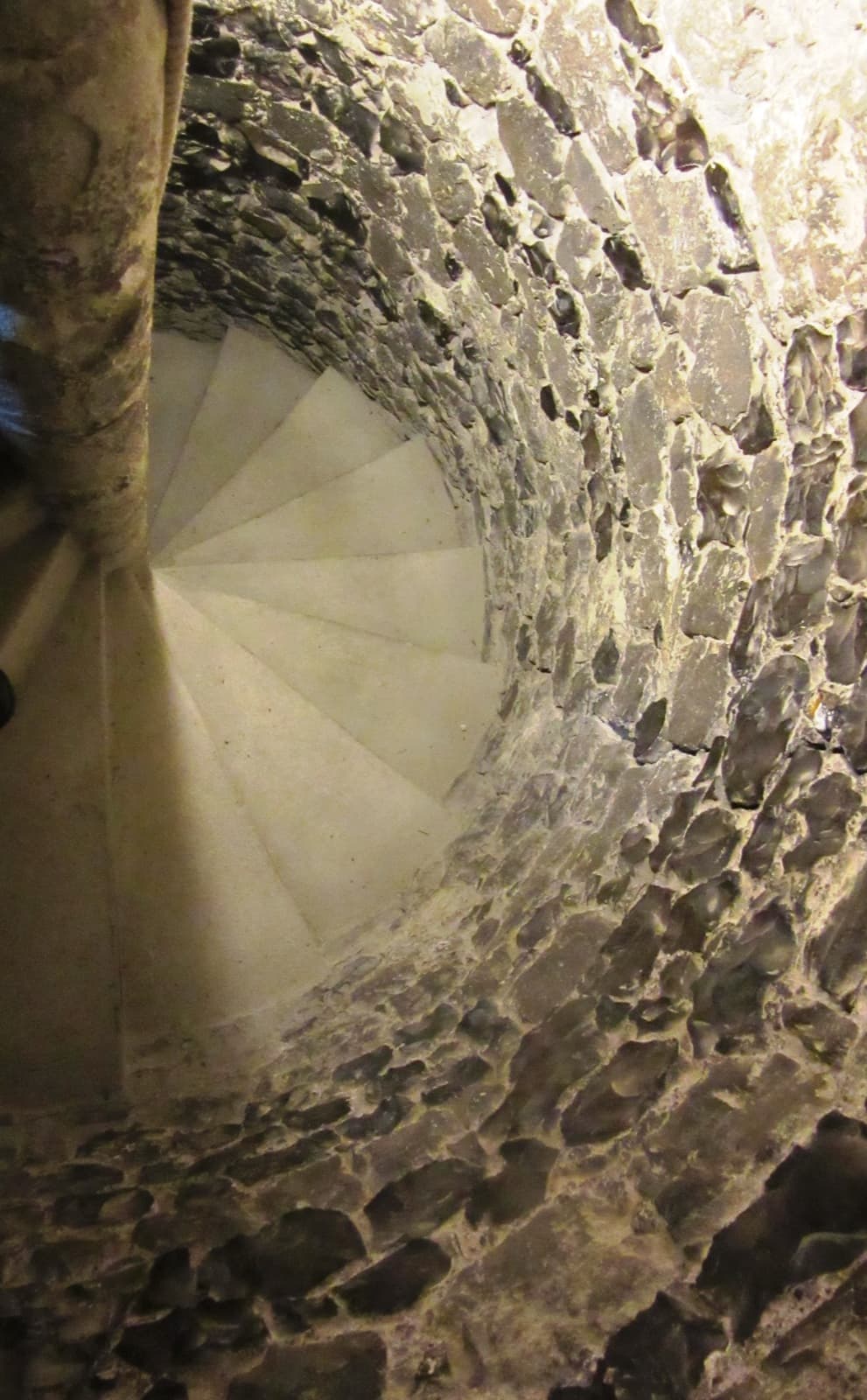 A narrow spiral stone staircase inside a tower, seen from above, curving out of sight.