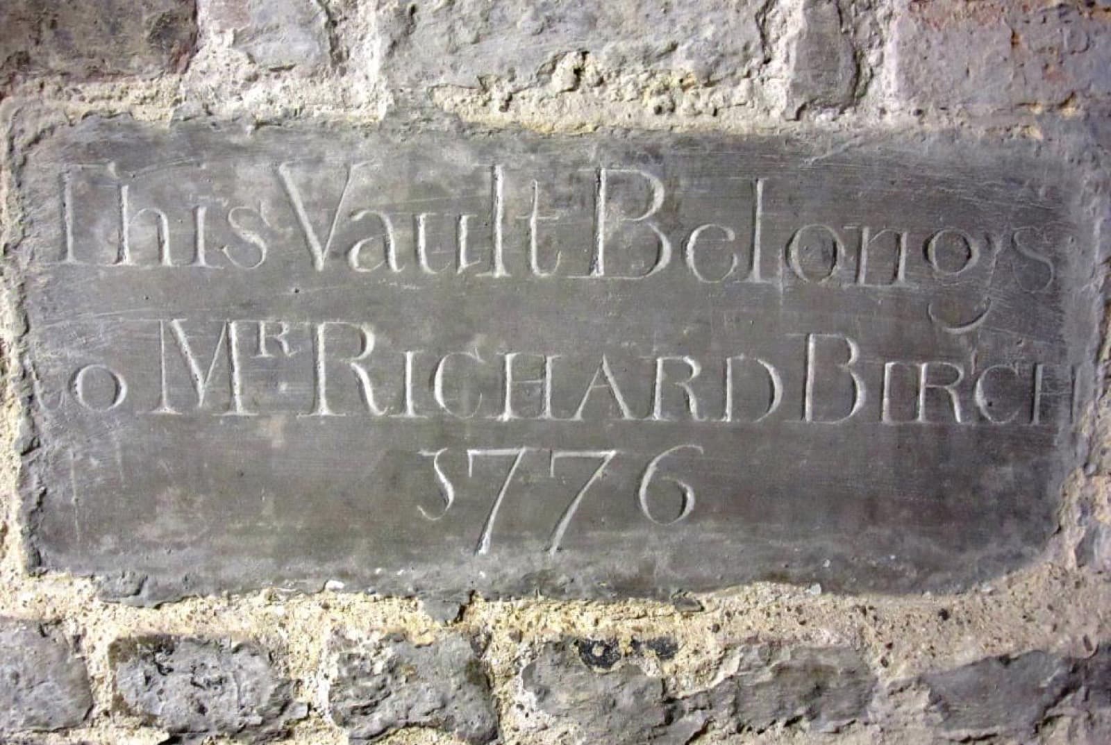 A stone slab set into a brick wall, cut with the words: This Vault Belongs to Mr Richard Birch 1776.