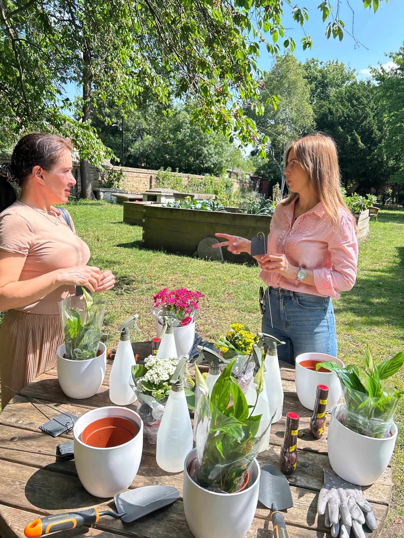 Volunteers at a table in the churchyard, potting up plants into white containers among trowels and gloves.